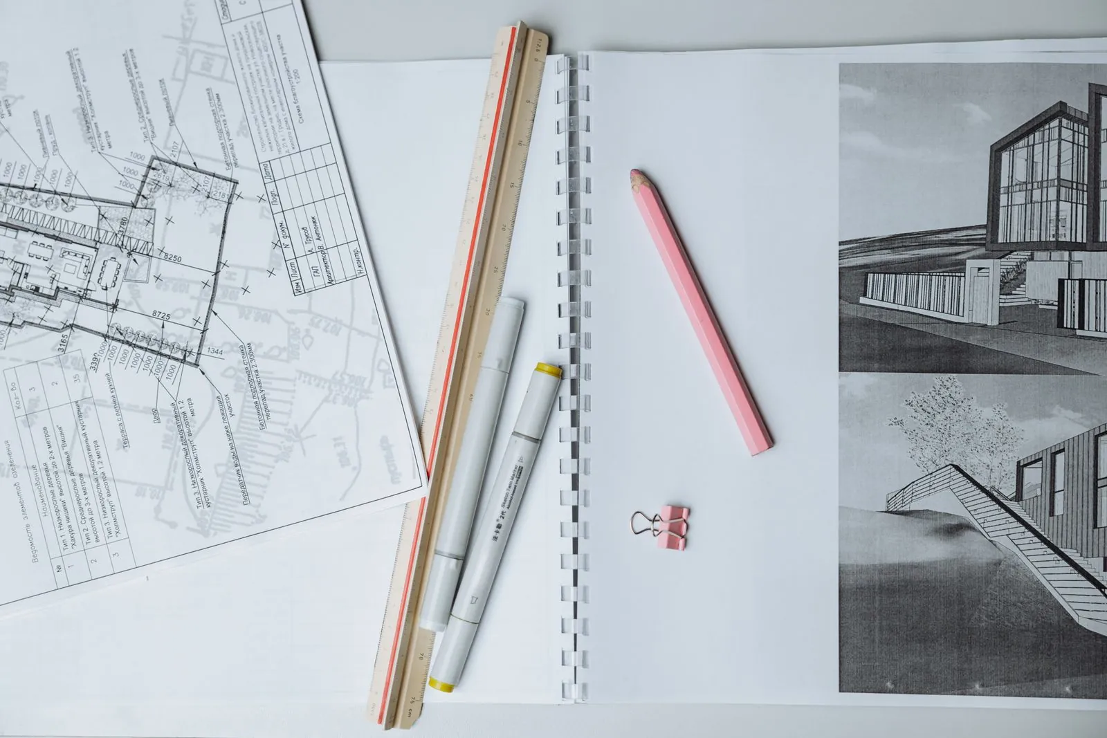 Technical floor plans, an architectural sketch, marker pens and a ruler laid out on a desk
